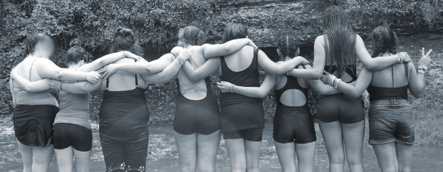 Photo of teenage girls holding each others' shoulders near a creek