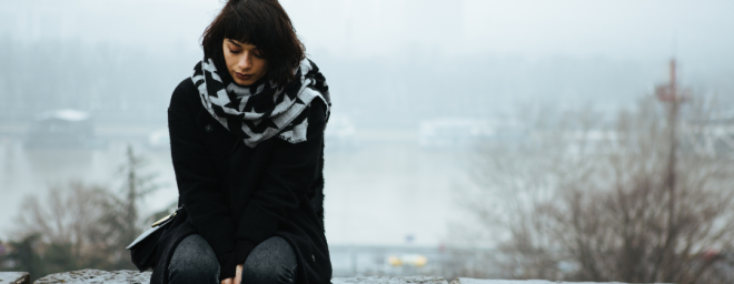 Young woman sitting on a bench outside in winter.