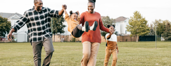 Black family playing together in an open field
