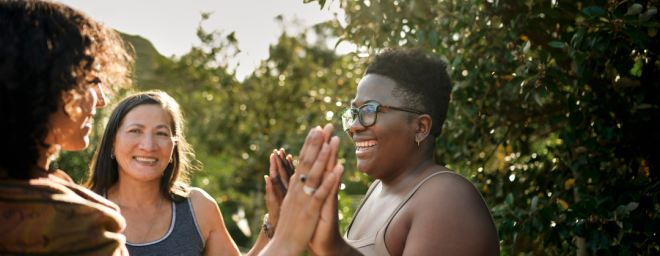 Three diverse women in a circle giving high fives.