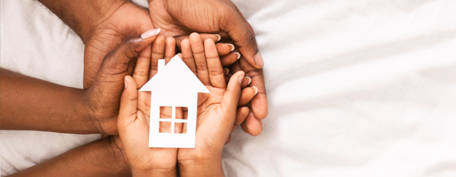 Parents and children's hands holding a house 